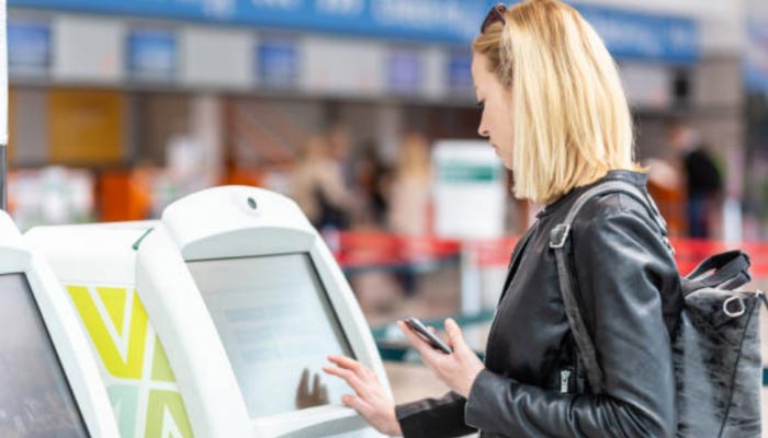 mulher fazendo check-in no tottem do aeroporto